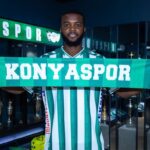 Footballer in green and white striped jersey holds a Konya Spor scarf in front of a trophy filled room  trybalnews