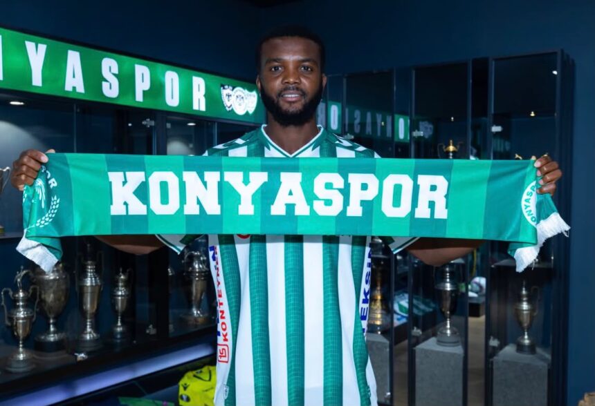 Footballer in green and white striped jersey holds a Konya Spor scarf in front of a trophy filled room  trybalnews