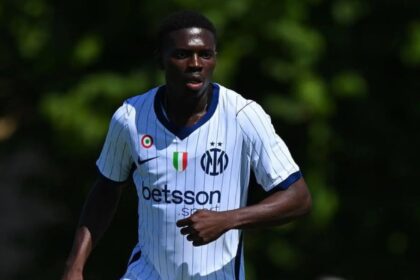 Soccer player in a white pinstripe jersey with blue trim, sprinting on a sunny field.