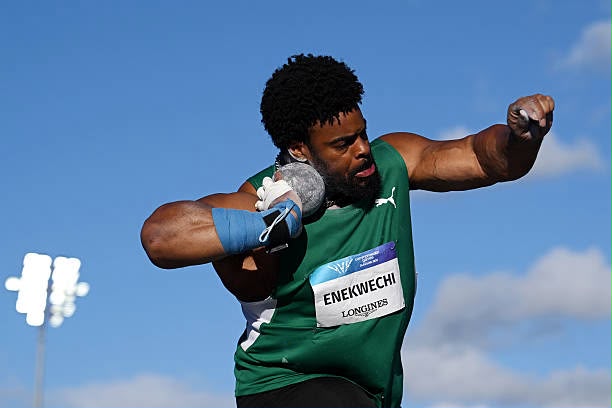 Male track and field athlete in a green uniform mid throw bib ENEKWECHI LONGINES against a blue sky background  trybalnews