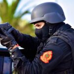 Tactical officer in helmet and body armor aims a pistol from a car window  trybalnews