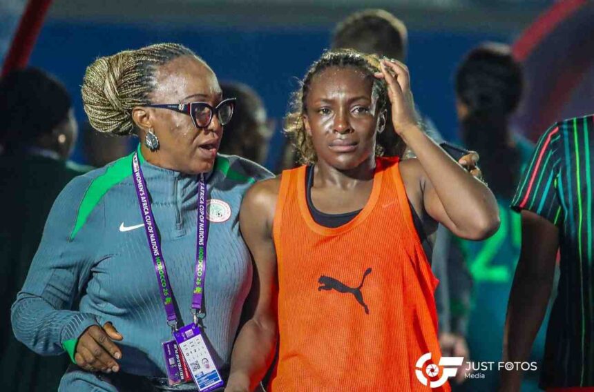 Female athlete in an orange jersey looks distressed as a coach with braided hair consoles her after a race in a sports venue Informative  trybalnews