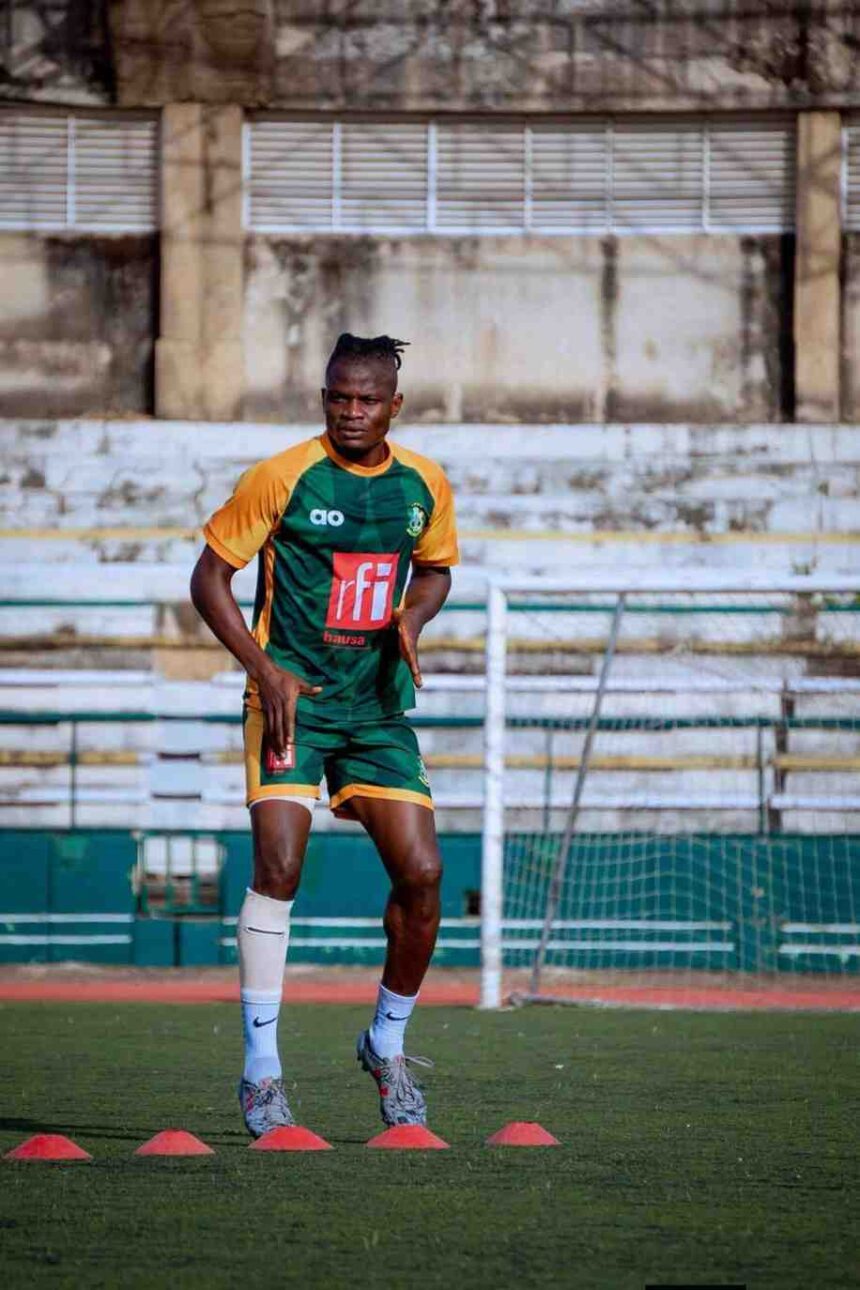 Male soccer player in green and orange kit performing an agility drill with orange cones on a training field  trybalnews