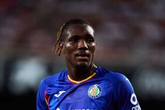 Close-up shot of Getafe CF footballer Chrisantus Uche looking ahead on the pitch while wearing a blue home kit during a LaLiga match.