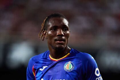 Close-up shot of Getafe CF footballer Chrisantus Uche looking ahead on the pitch while wearing a blue home kit during a LaLiga match.
