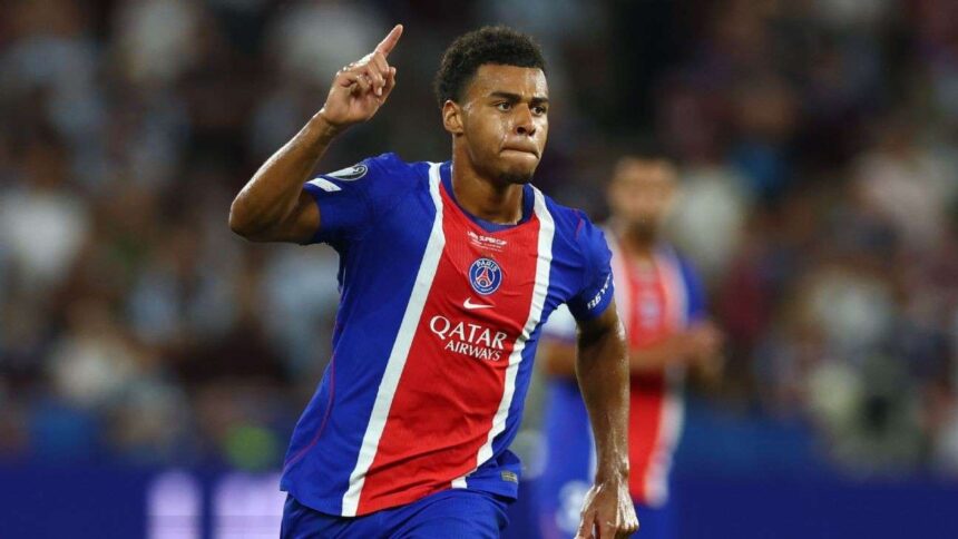 Soccer player in blue and red jersey points upward during a celebration on the field  trybalnews