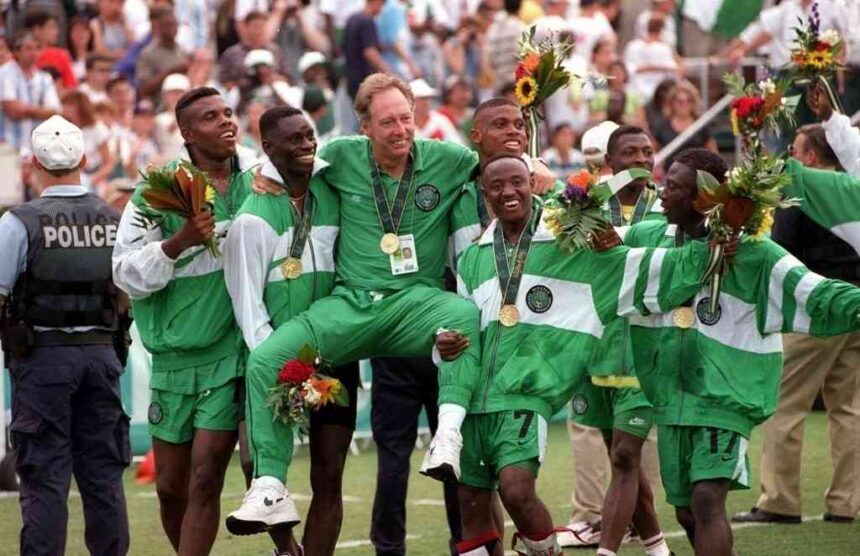 Nigerias head coach Johannes Bonfrere is chaired in the air by his players wearing green and white tracksuits after Nigeria beat Argentina 3 2 in the Football Final at the 1996 Olympic Games in Atlanta USA The gold medalists smile hold bouquets and wear gold medals around their necks while celebrating on the pitch with fans in the background  trybalnews