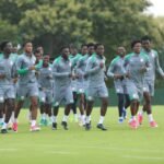 Group of athletes in gray training gear jogging across a grassy practice field  trybalnews