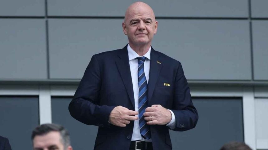Man in a dark suit and striped tie stands outside adjusting his jacket  trybalnews