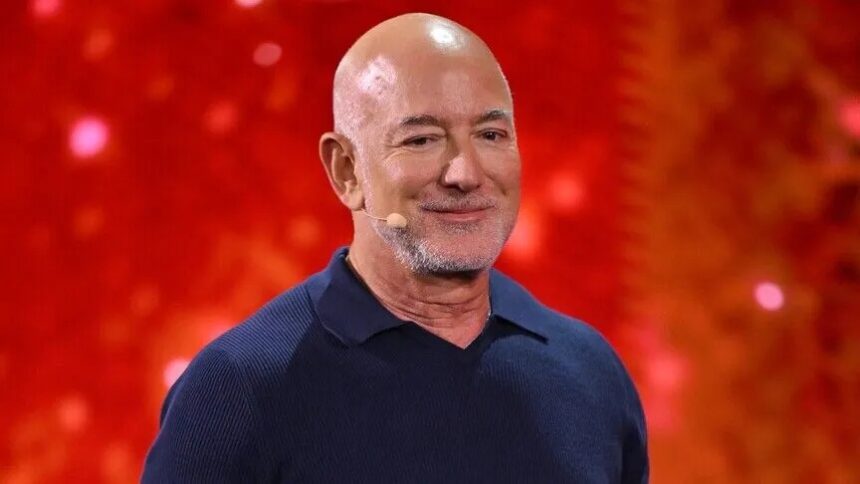 Bald man wearing a navy polo on stage with a red glittery background and a small headset microphone on his cheek  trybalnews