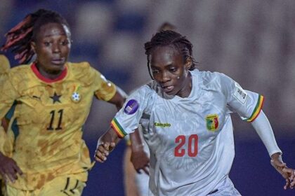 Female soccer players sprint for the ball in a match; white jersey with number 20 leads a chase against a yellow-jersey opponent (no. 11).