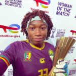 Female Cameroon footballer selfies after a win wearing a purple jersey and headband holding a tall gold trophy  trybalnews