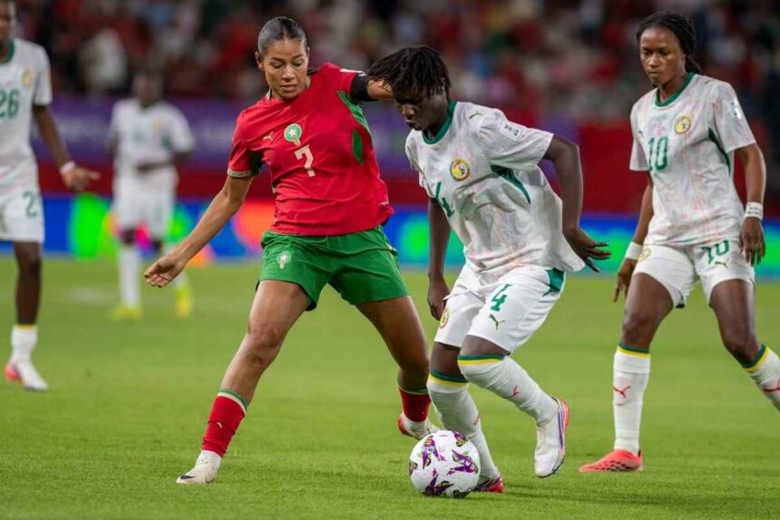 Female soccer players compete for the ball during a match player in red jersey number 2 and green shorts challenges a white jersey opponent near the ball on a green field  trybalnews