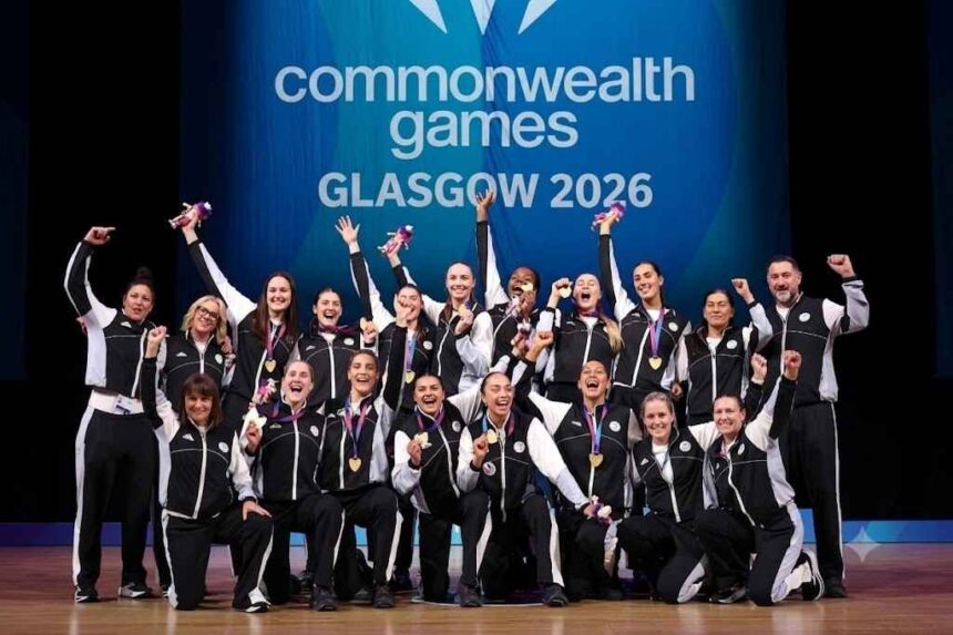 Gold medalists of Team New Zealand celebrate during the Netball medal ceremony on Day 10 of the Glasgow 2026 Commonwealth Games at The Hydro, August 2, 2026. Players and coaches in black and white tracksuits pose together on stage, holding up gold medals and Commonwealth Games mascots with a "Commonwealth Games GLASGOW 2026" backdrop behind them.