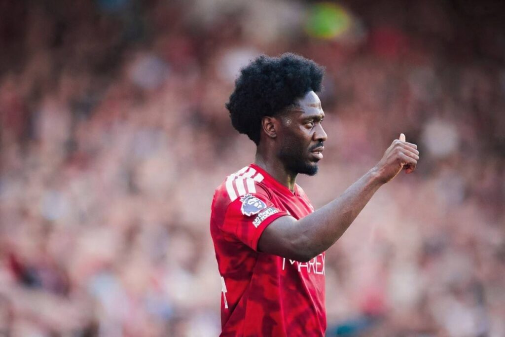 Ola Aina Trybal News Nottingham Forest player Ola Aina in a red home jersey gestures with his right hand during the Premier League 202627 match between Nottingham Forest FC and Leeds United at the City Ground on August 22 2026 in Nottingham England trybalnews