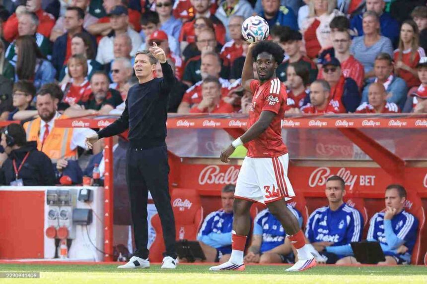 Nottingham Forest manager Oliver Glasner left in a black tracksuit gives instructions as player Ola Aina wearing a red home kit prepares to take a throw in during a Premier League match at the City Ground in Nottingham on Saturday August 22 2026  trybalnews