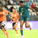 Two female soccer players chase the ball during a match green Nigeria kit 8 vs orange kit 23  trybalnews
