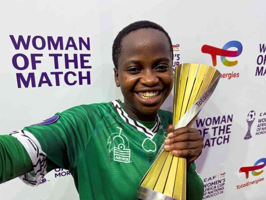 Smiling female athlete in a green jersey holds a gold trophy at a Woman of the Match event backdrop  trybalnews