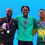 Gold medalist Samuel Ogazi of Team Nigeria in a green Puma tracksuit with the Nigerian flag stands in the center on the podium with his arm around silver medalist Jereem Richards of Trinidad and Tobago in a black jacket on the left and bronze medalist Zakithi Nene of South Africa in a green and yellow tracksuit on the right All three hold medals and Commonwealth Games mascots during the Mens 400 Metres Final medal ceremony on Day 9 of the Glasgow 2026 Commonwealth Games at Scotstoun Stadium August 1 2026  trybalnews