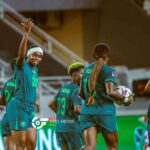 Nigerias Super Falcons player Monday Gift wearing jersey number 20 and a white headband raises her hand and celebrates with teammates after scoring the teams second goal during a WAFCON Group C match against Egypt Other Nigerian players in teal and green kits are running and celebrating on the pitch in a stadium  trybalnews