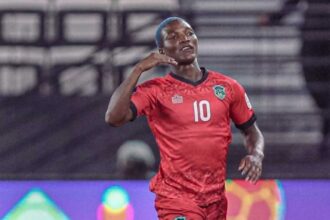 Soccer player in a red jersey with the number 10 celebrating a goal on the pitch.