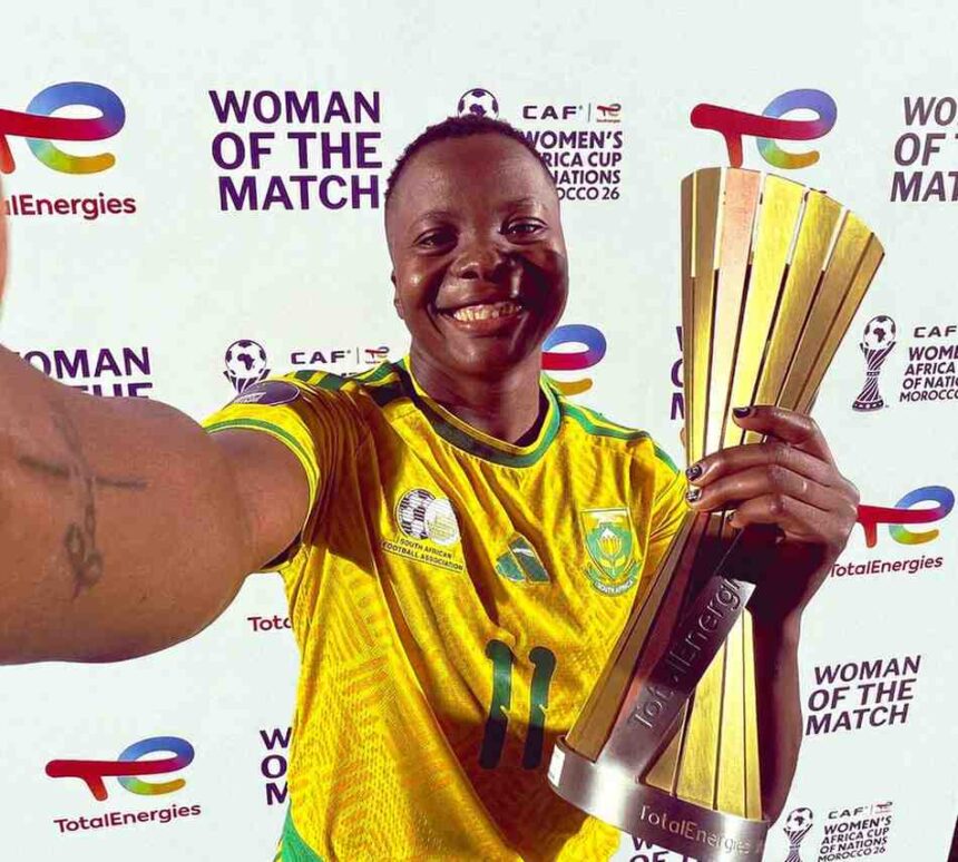Female soccer player in a yellow jersey posing with a tall gold trophy smiling against a Woman of the Match backdrop  trybalnews