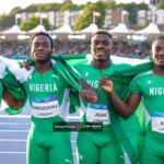 Four Nigerian male sprinters in green Nigeria jerseys pose with arms around each other after a race smiling on a track with crowd in the background  trybalnews