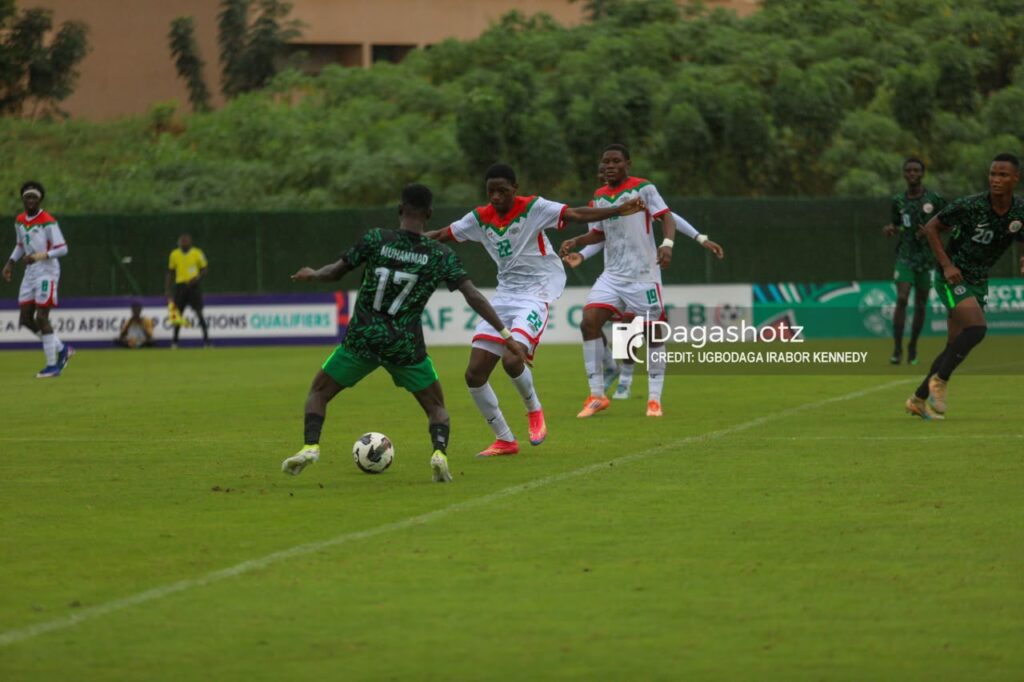 Flying Eagles Trybal News Soccer players in green and white uniforms contesting the ball on a grassy field during a match with a defender challenging a attacker near the ball trybalnews