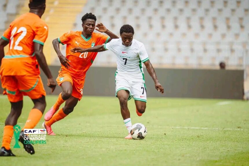Soccer players in orange and white chase a ball on a green field during a CAF U 20 Africa Cup qualifying match with one player in white dribbling  trybalnews