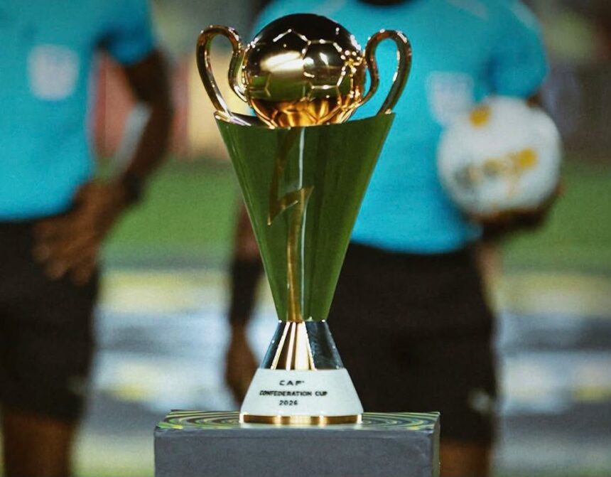 Gold trophy with two handles on a pedestal labeled CAP Conference Cup 2026 foreground with blurred players in teal shirts in the background  trybalnews