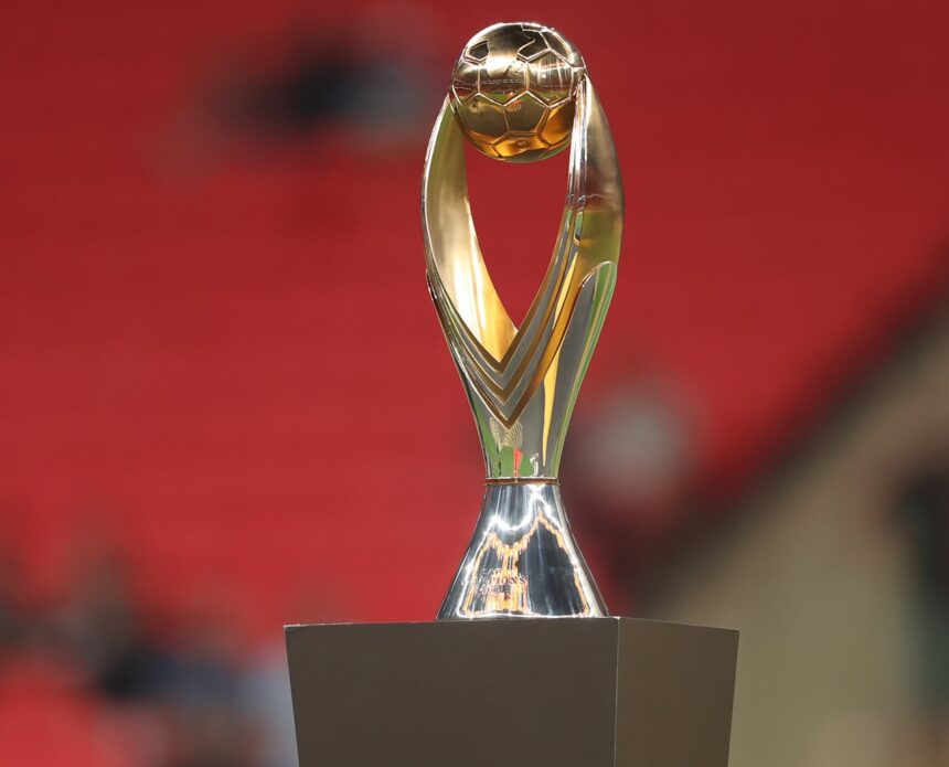 Golden trophy with a spherical top and curved arms on a square base against a red blurred background  trybalnews