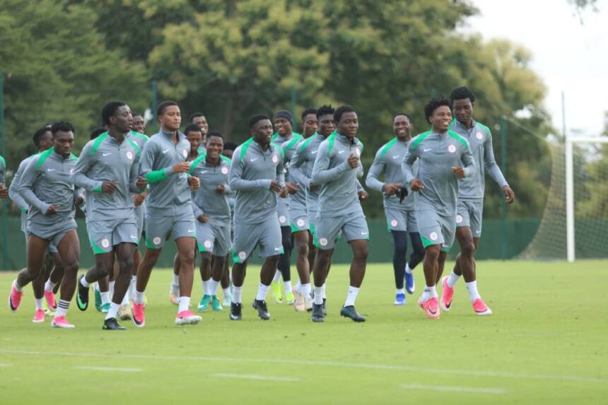 Group of male soccer players in gray and green training outfits running together on a grass field during practice  trybalnews