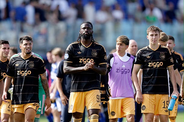 Soccer players in black Ziggo jerseys walk together on the field before spectators in the stands  trybalnews
