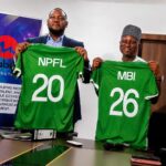 Two men hold up green sports jerseys with numbers 20 and 26 symbolizing team players during a signingpress event  trybalnews