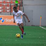 Soccer player in a white kit with red trim dribbling a yellow ball on a green field during a match  trybalnews