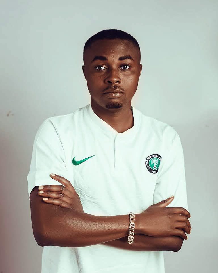 Portrait of a young man with short hair arms crossed wearing a white soccer jersey with a green Nike swoosh and a club badge on the chest  trybalnews