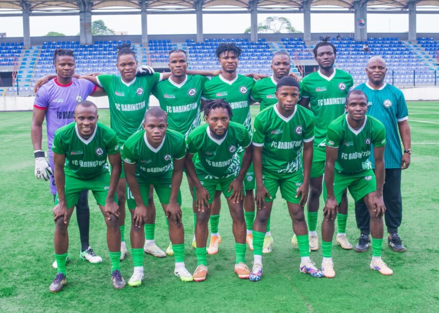 Group of soccer players in green uniforms posing for a team photo on a field with empty blue stadium seats in the background  trybalnews