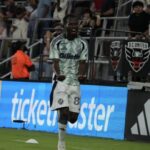 Soccer player in a mint green jersey number 88 celebrating on the field with fans in the stands behind him  trybalnews