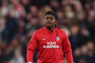 Ademola Lookman of Atletico de Madrid wearing a red and white striped jersey and blue shorts warms up during half time on the pitch at Anfield during the UEFA Champions League 2026/27 League Phase match between Liverpool FC and Atletico de Madrid on September 9, 2026 in Liverpool, England.