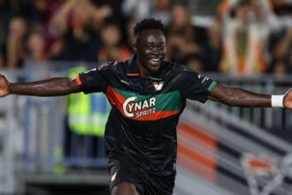 Akor Adams of Venezia FC in a black, green and orange jersey with number 4 celebrates with arms outstretched after scoring the opening goal during the Serie A match between Venezia and ACF Fiorentina at Stadio Pier Luigi Penzo on September 11, 2026 in Venice, Italy.
