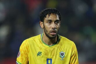 Gabon forward Pierre-Emerick Aubameyang reacts during the Africa Cup of Nations Group F match between Cameroon and Gabon at Adrar Stadium in Agadir on December 24, 2025. The striker wears Gabon's yellow home jersey with blue number 9 and the FEGAFOOT crest, with a blurred stadium crowd in the background.