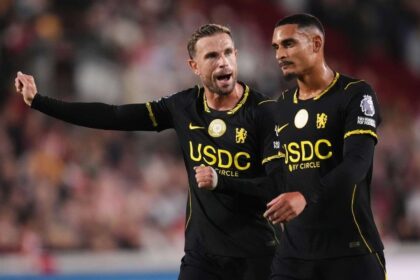 Chelsea's Jordan Henderson, left, gestures and shouts while directing play alongside teammate Maxence Lacroix. Both players wear Chelsea's black away kit with yellow USDC by Circle sponsorship during the Premier League match at the Gtech Community Stadium in Brentford on September 18, 2026.