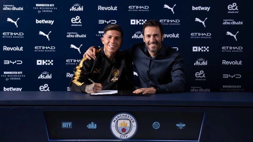 Enzo Fernandez signs his contract as a new Manchester City player at a signing table wearing a black and gold training top He is seated next to a Manchester City official with an arm around his shoulder The backdrop features Manchester City and sponsor logos including Etihad Puma and Betway  trybalnews