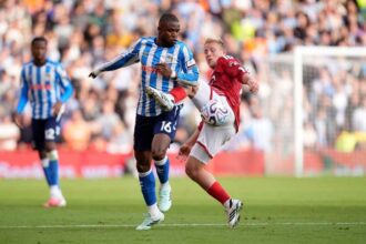 Coventry City midfielder Frank Onyeka, wearing number 16 in a blue and white striped shirt, challenges Nottingham Forest midfielder Xaver Schlager in a red shirt for possession of the ball during the Premier League match at the City Ground.