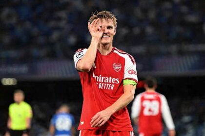 Martin Odegaard, captain of Arsenal FC, celebrates wearing a red home jersey and green captain's armband during the UEFA Champions League 2026/27 League Phase match between SSC Napoli and Arsenal FC at Stadio Diego Armando Maradona in Naples, Italy on September 9, 2026.