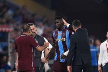 Trabzonspor striker Paul Onuachu wearing a maroon and light blue jersey with number 30 walks off the pitch injured, surrounded by coaching staff, during the Turkish Süper Lig week 4 match between Trabzonspor and Gençlerbirliği at Papara Park in Trabzon, Türkiye on September 6, 2026.