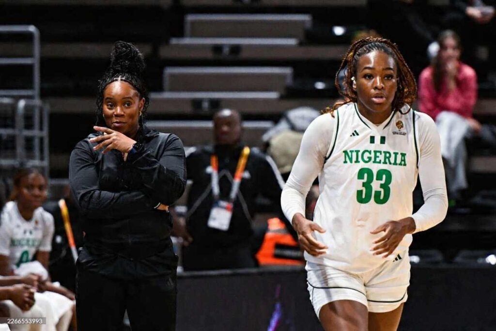 Rena Wakama head coach of Nigeria stands on the sideline and gestures during the FIBA Womenaposs Basketball World Cup 2026 Qualifiers match between Nigeria and Germany at The Astroballe in Villeurbanne France on March 17 2026 A Nigeria player wearing white jersey 33 is on the court beside her with empty stadium seats in the background  trybalnews