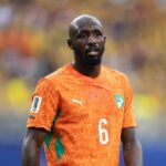 Close up of Seko Fofana of Cote dIvoire wearing an orange number 6 jersey with green accents during the FIFA World Cup 2026 Group E match between Cote dIvoire and Ecuador at Philadelphia Stadium on June 14 2026 He has a bald head and beard and is looking forward on the pitch with a blurred stadium crowd in the background  trybalnews