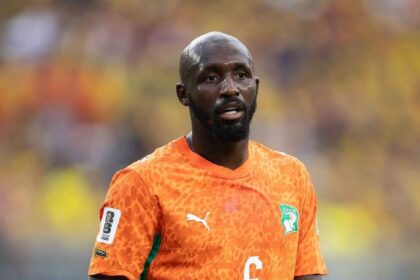 Close-up of Seko Fofana of Cote d'Ivoire wearing an orange number 6 jersey with green accents during the FIFA World Cup 2026 Group E match between Cote d'Ivoire and Ecuador at Philadelphia Stadium on June 14, 2026. He has a bald head and beard, and is looking forward on the pitch with a blurred stadium crowd in the background.