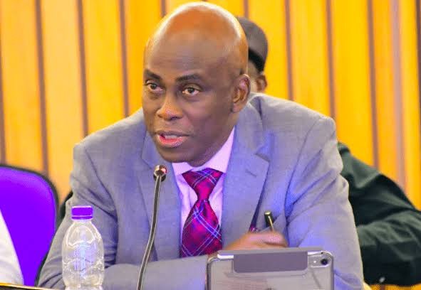 Adesoji Tayo President of the Nigeria Table Tennis Federation wearing a grey suit and purple patterned tie speaking into a microphone during a meeting  trybalnews